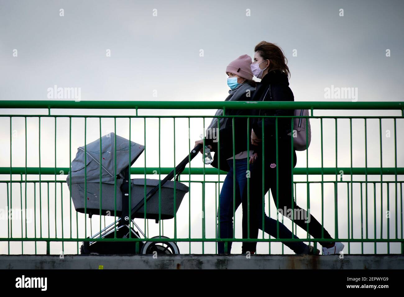 (210228) -- WARSAW, Feb. 28, 2021 (Xinhua) -- Two women wearing face masks are seen with a stroller crossing a bridge in Warsaw, Poland, on Feb. 27, 2021.  The Polish government announced new restrictions on Wednesday in an effort to curb a recent rise in new COVID-19 infections officially dubbed the 'third wave.'   Health Minister Adam Niedzielski said that the rules on face covering will be tightened, mandating the use of masks in public spaces starting on Saturday instead of the previously allowed alternatives, such as scarfs and visors.   Also starting on Saturday, travelers from southern Stock Photo