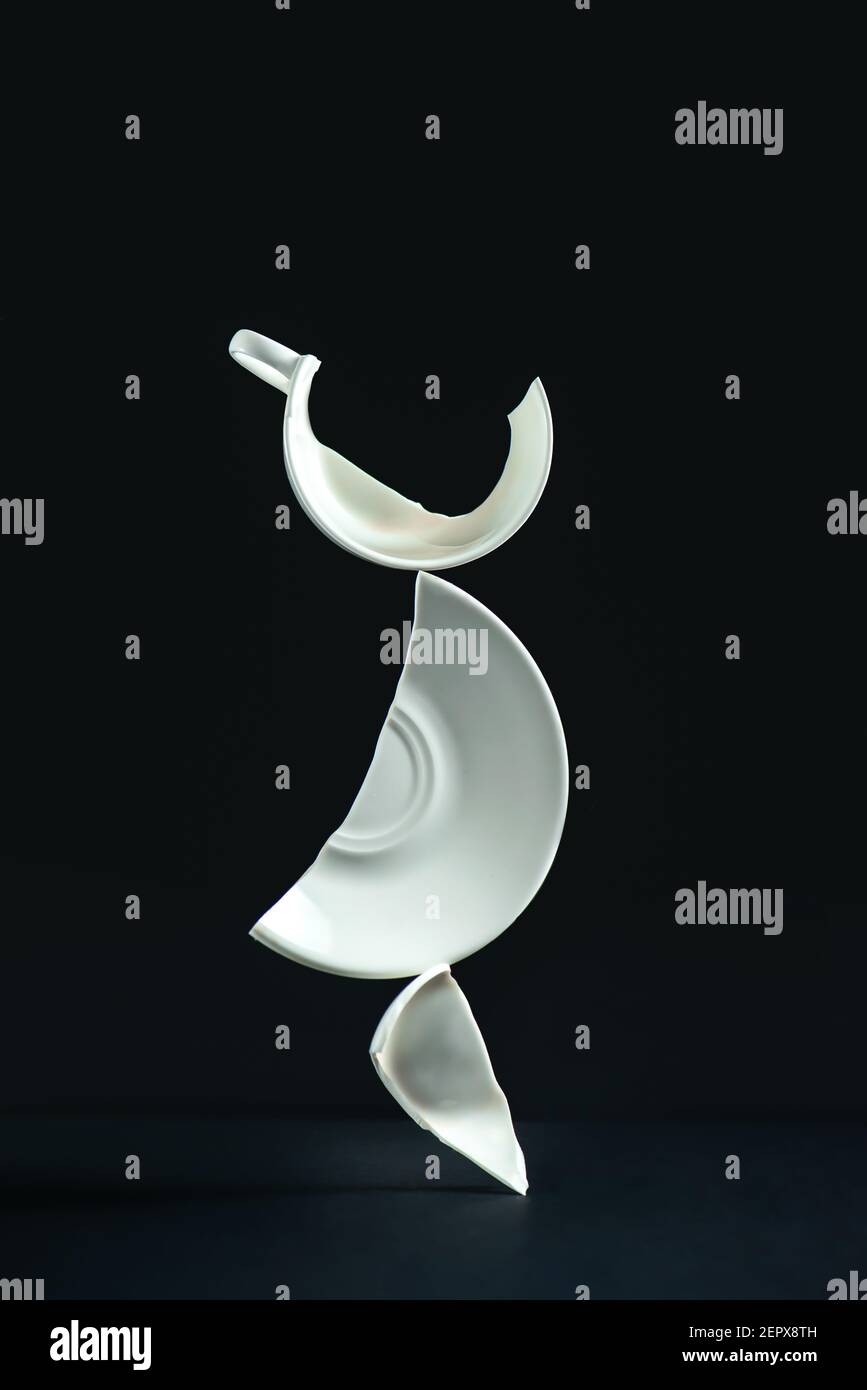 Broken cup balancing construction, porcelain shards on a black background Stock Photo