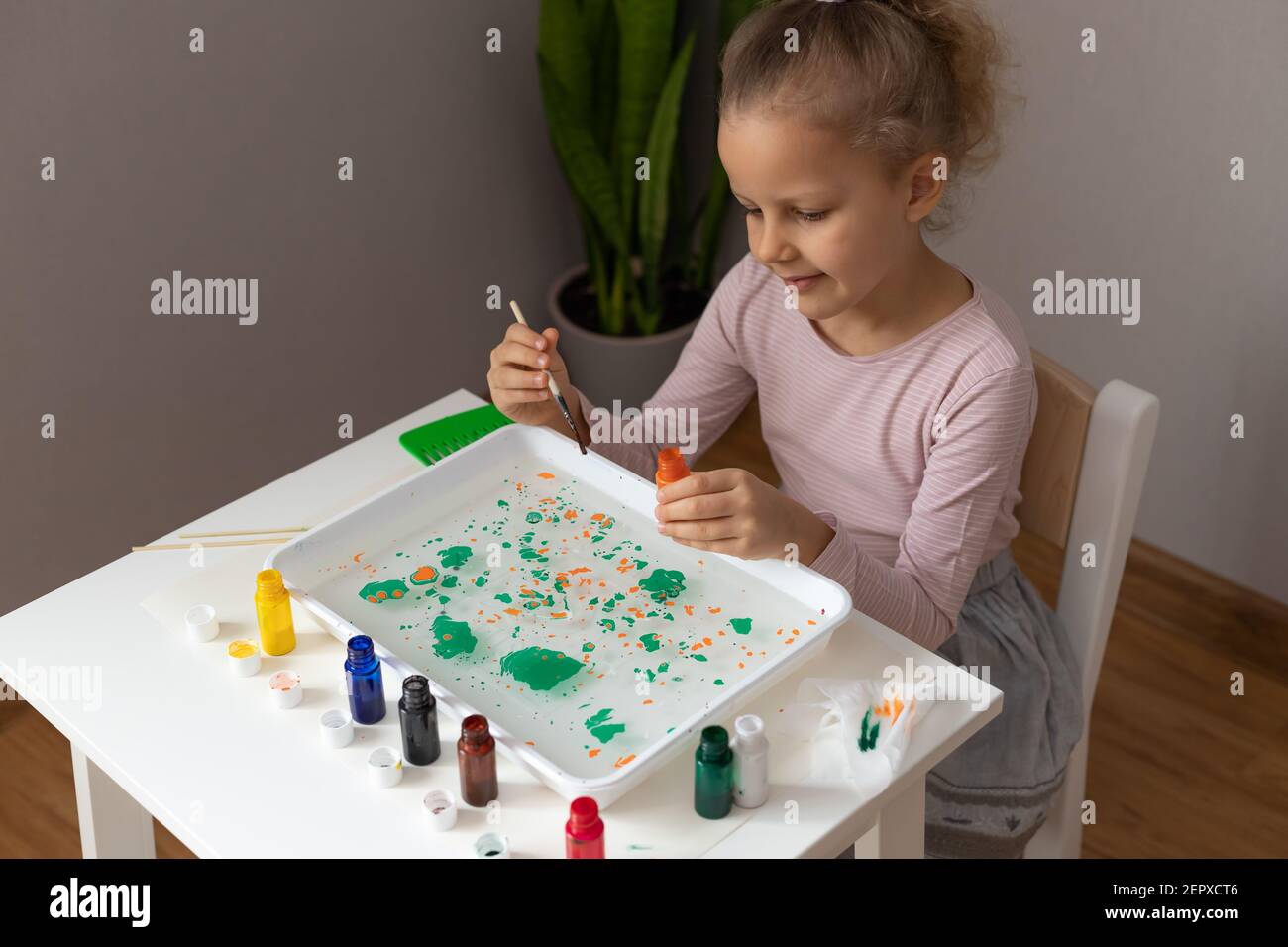 little girl painting with ebru paints Stock Photo