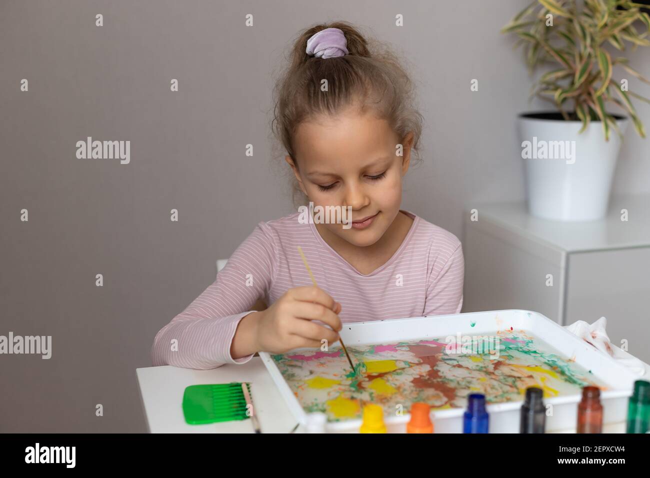 preschooler girl painting with paints on water Stock Photo