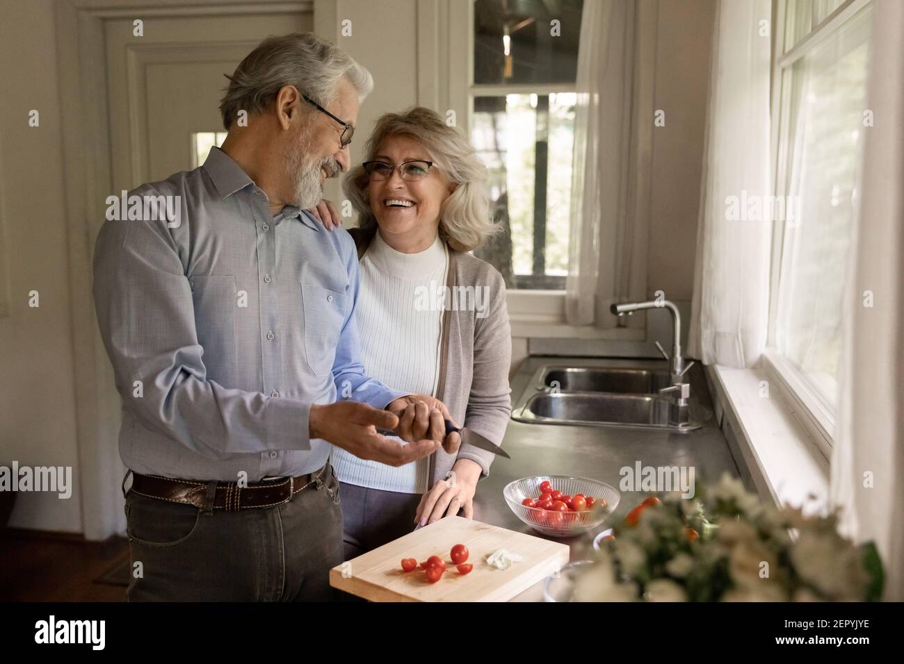 Happy middle aged couple of vegans cooking dinner together Stock Photo