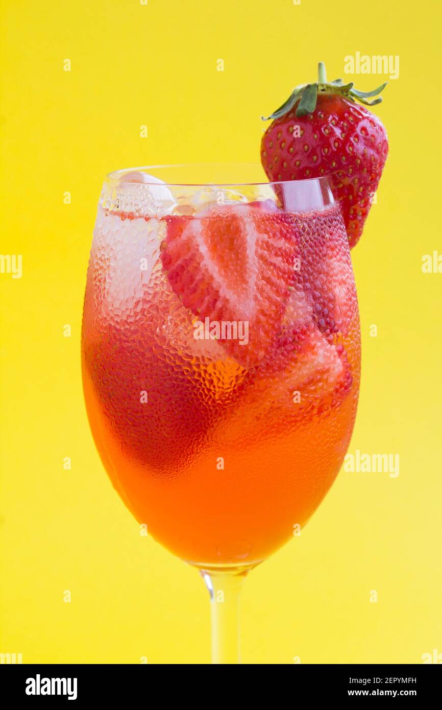 Cocktail drink with strawberry and ice in a glass on the yellow  background. Location vertical. Closeup. Stock Photo