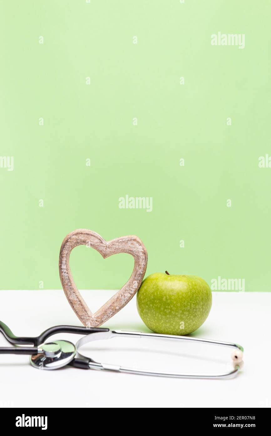 Apple, heart and stethoscope on vertical green and white background ...