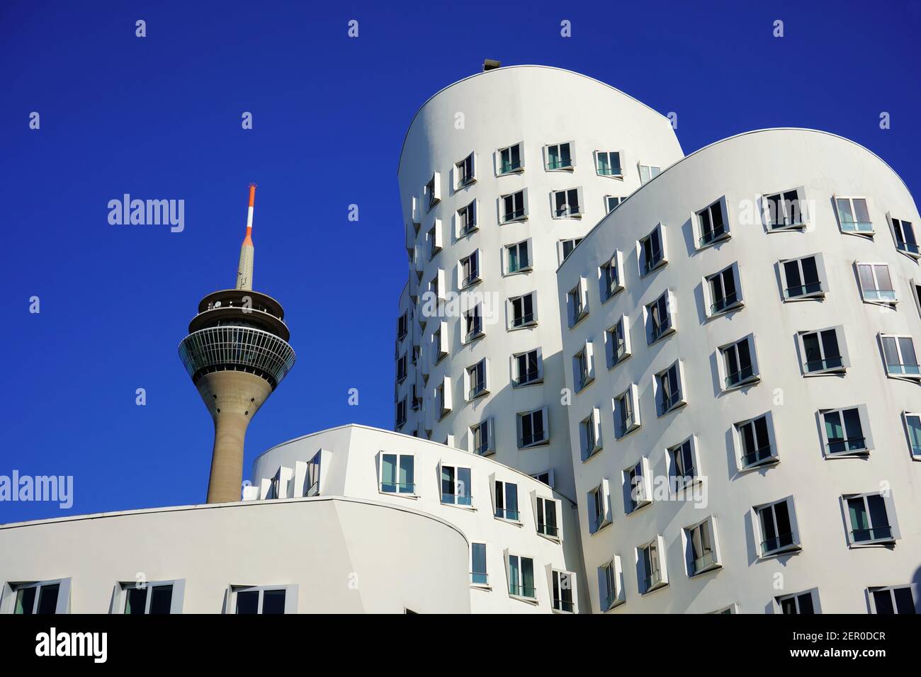 White buildings designed by the star architect Frank O. Gehry at 'Neuer Zollhof', Medienhafen, and Rhine Tower, Düsseldorf's landmark. Stock Photo
