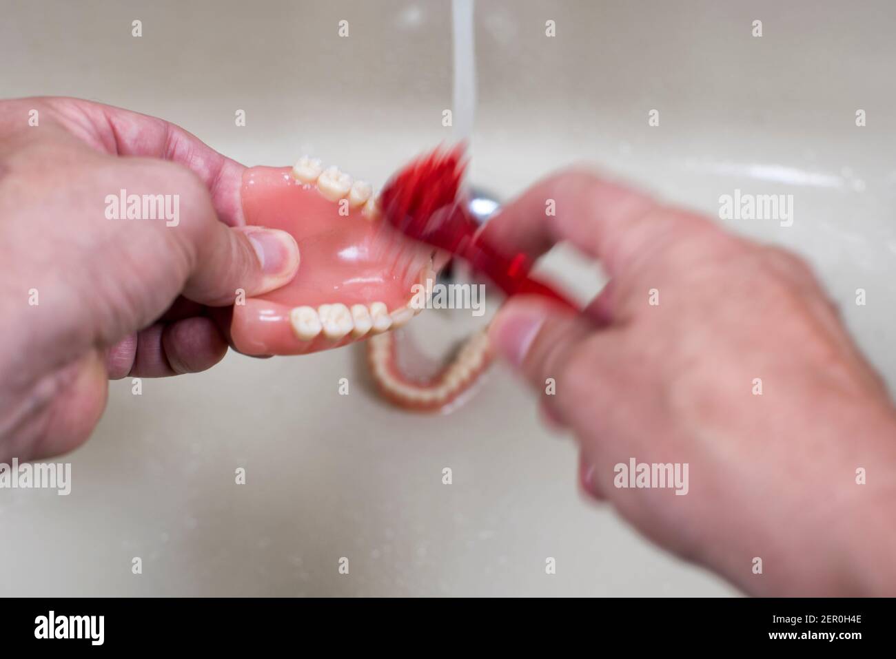 Cleaning and washing of the teeth dentures in the sink with the running
