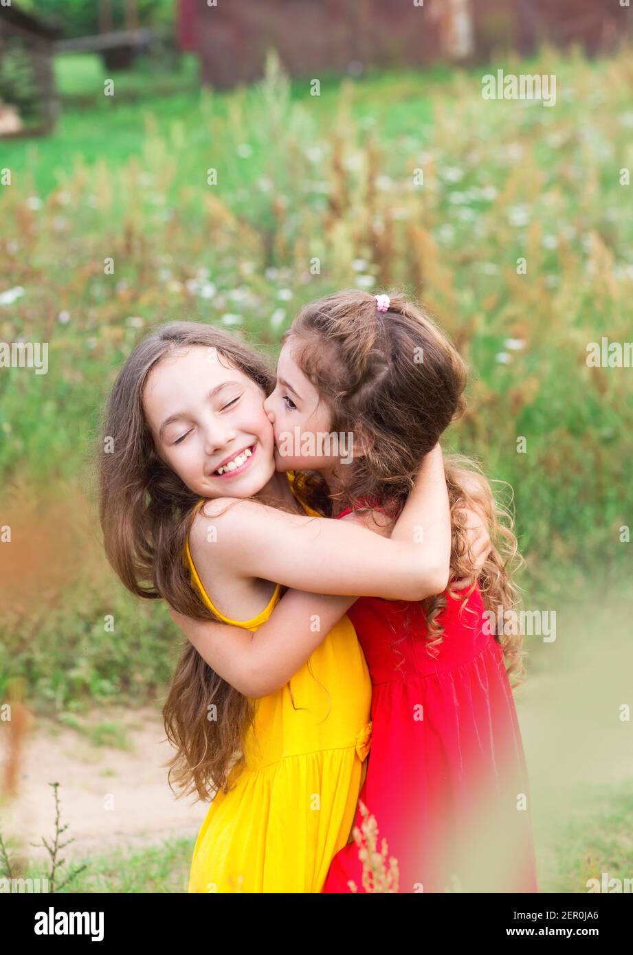 Portrait of Two Cute little girls embracing and laughing at the field. Happy kids outdoors Stock Photo