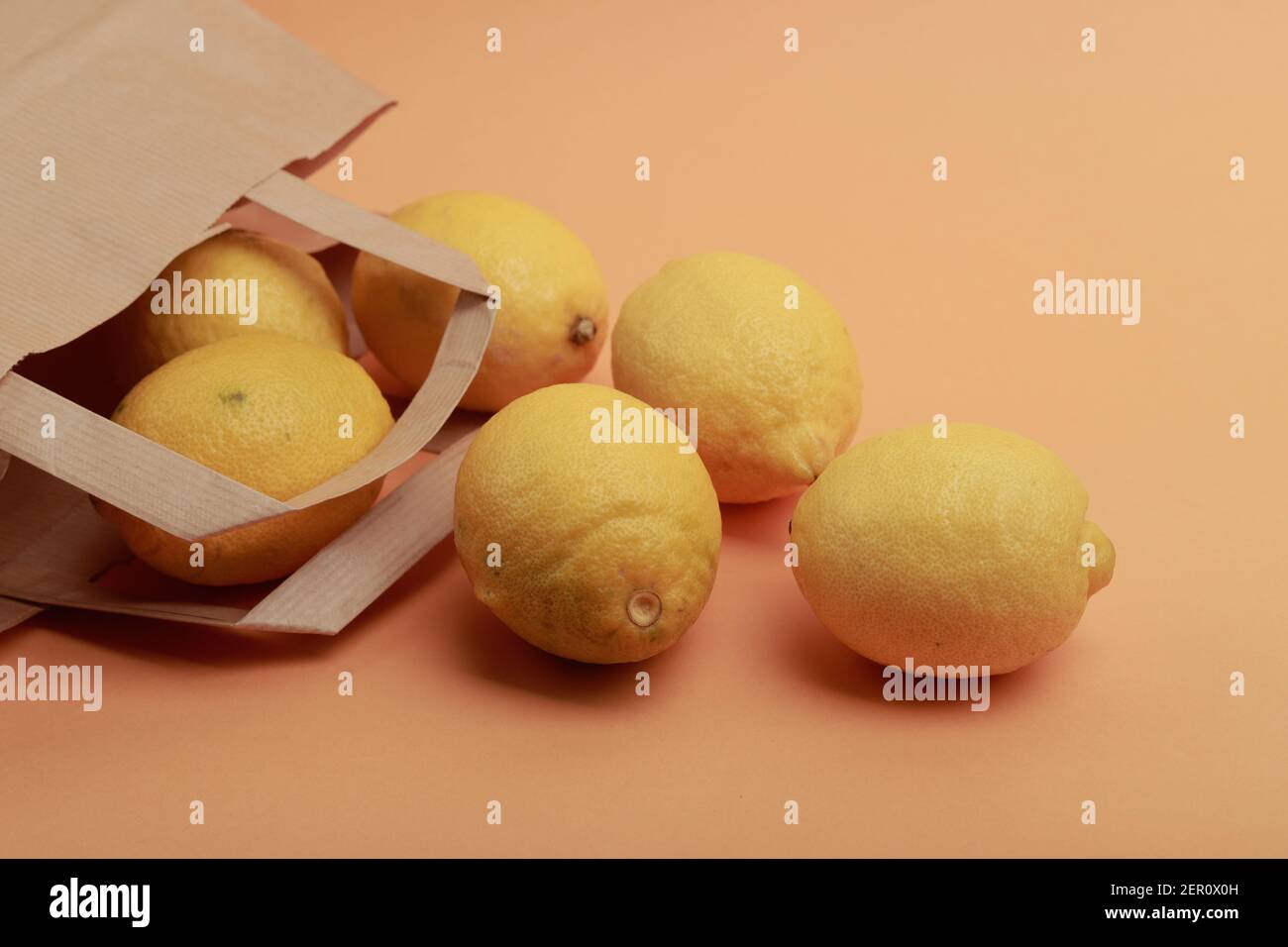 photo of lemon coming out of a supermarket paper bag on orange background and pastel colors Stock Photo