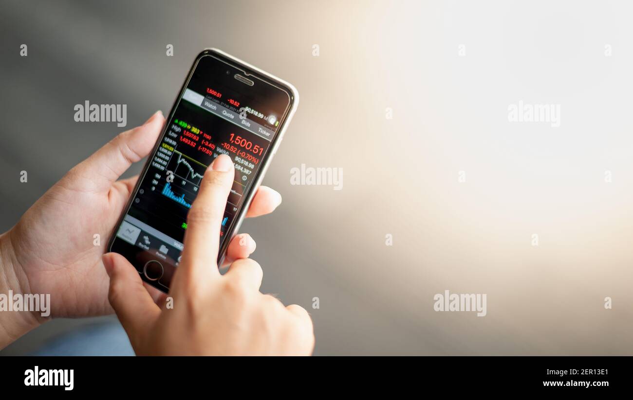 Close-up hand holding mobile phone with analyzing graph and the ...