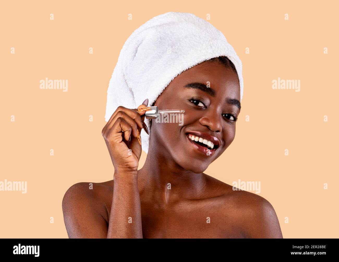 Black lady applying moisturizer or hyaluronic acid on face Stock Photo