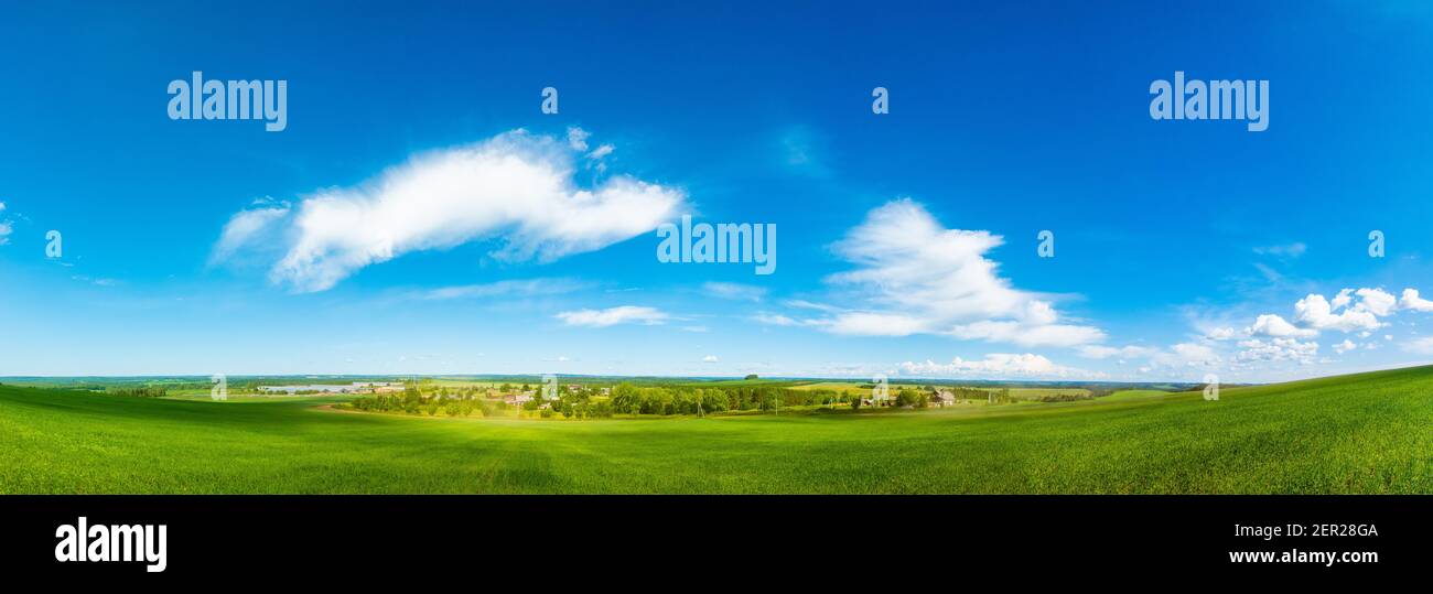 Panorama of a green field and sky. Sunny summer landscape of a European village Stock Photo