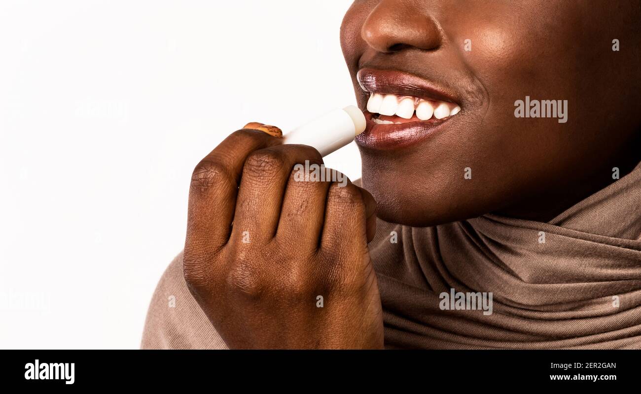 Black woman applying hygienic lip balm on light background Stock Photo