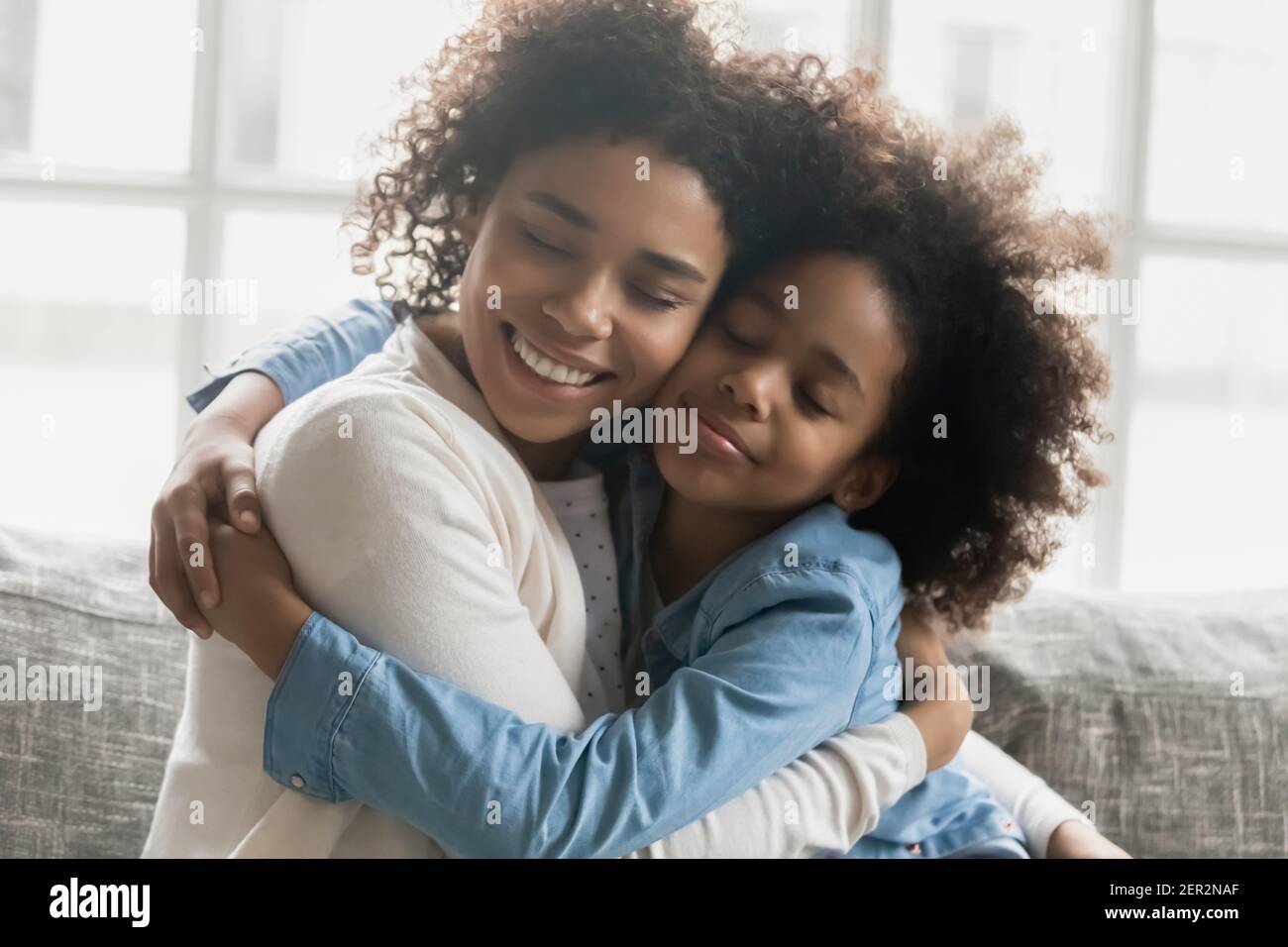 Portrait of happy mom with shut eyes embracing daughter girl Stock Photo