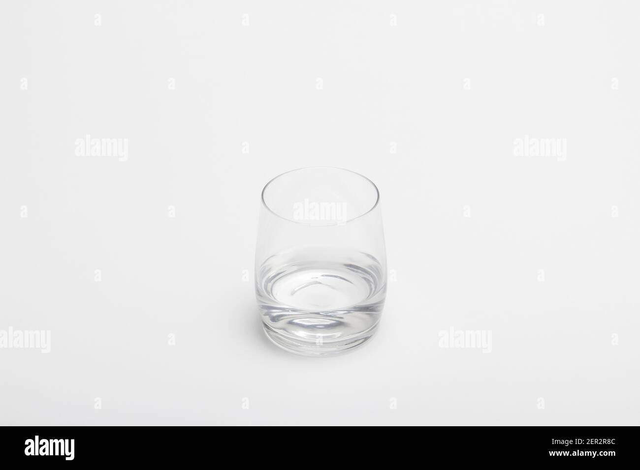 The half full glass of pure water isolated on a white background. A drinking glass half filled with water. A half empty glass with water. Stock Photo