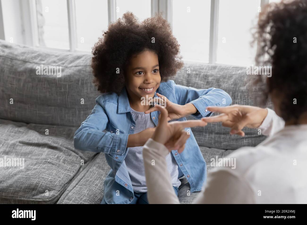 Happy Black girl talking to disabled deaf mom Stock Photo