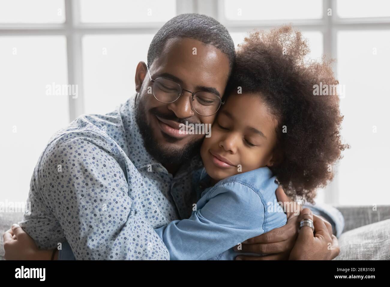 Portrait of happy cute Black girl hugging her beloved daddy Stock Photo