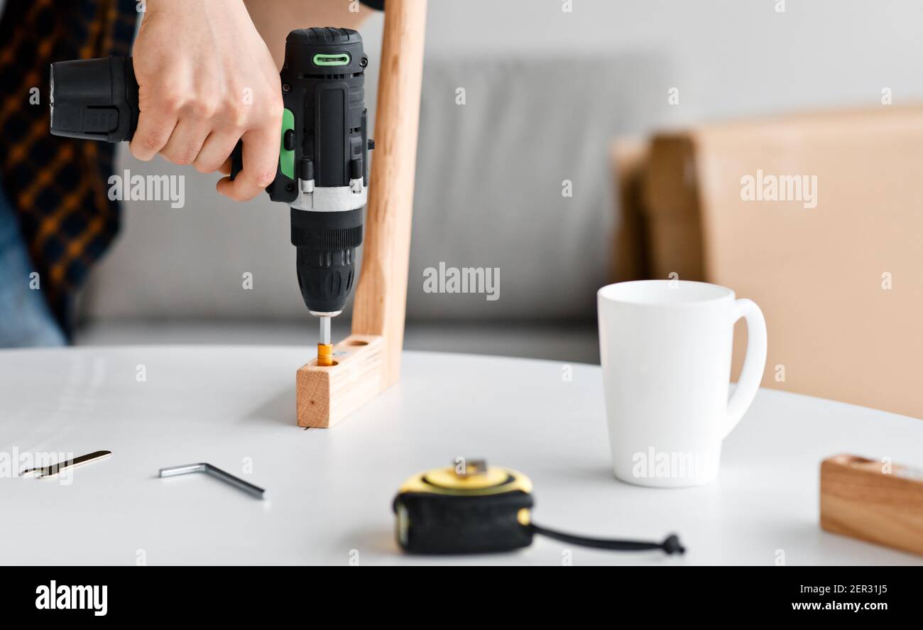 Repairman assembling and fixing furniture during renovation, furnishing and assembly service Stock Photo