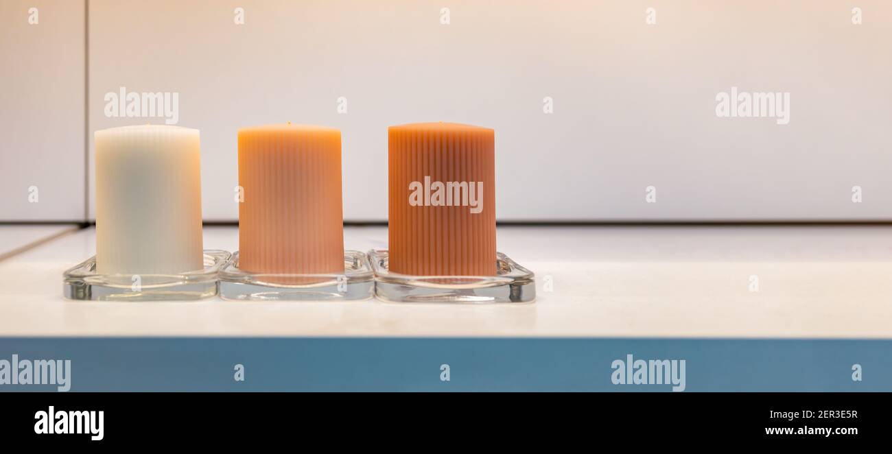 close up of white, orange and dark orange candles on white shelf Stock Photo