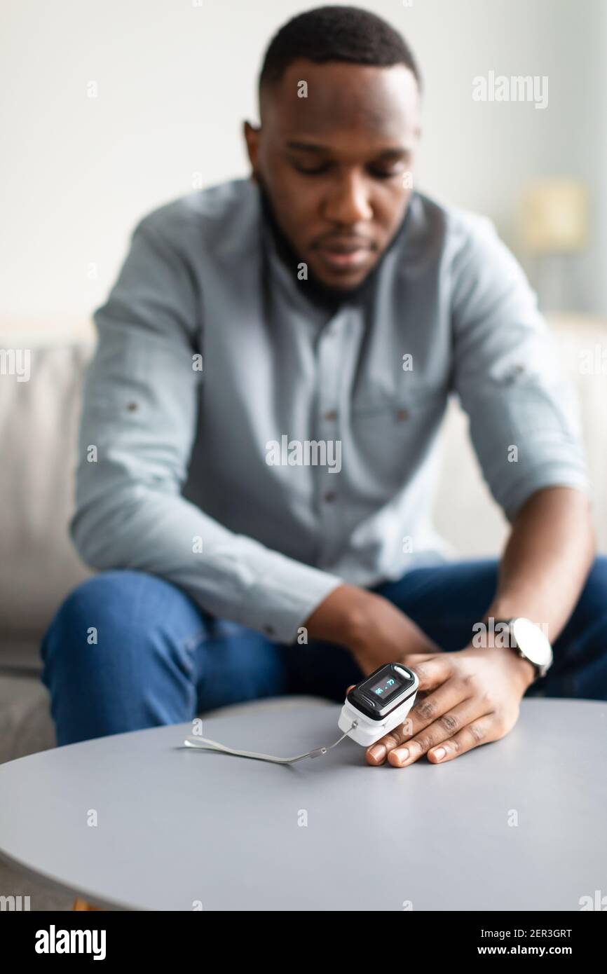 Black Man Measuring Oxygen Saturation Level With Pulse Oximeter Indoors Stock Photo