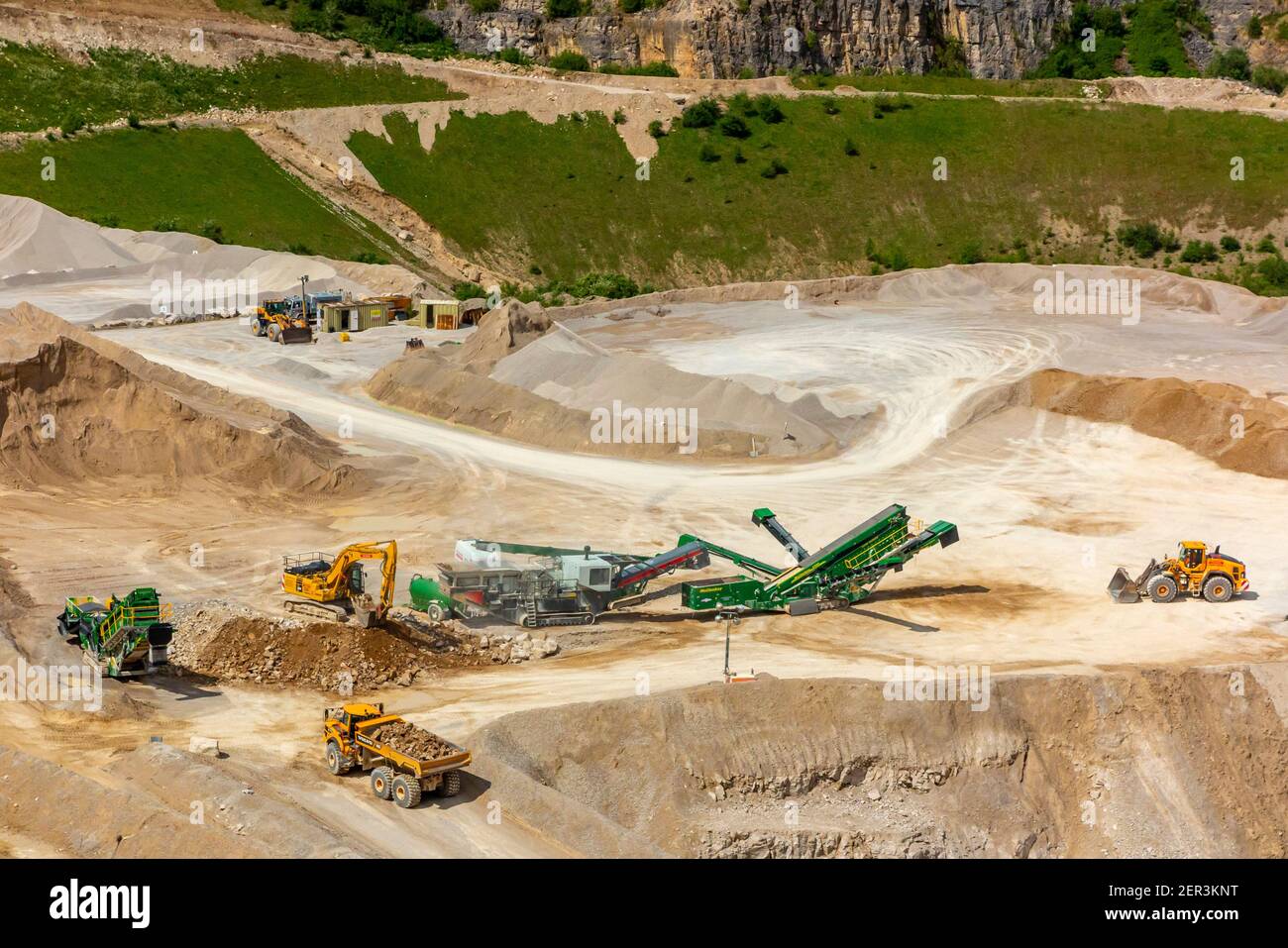 Diggers and earth moving trucks with quarrying machinery at Dene Quarry in Cromford near Matlock in the Derbyshire Dales England UK Stock Photo