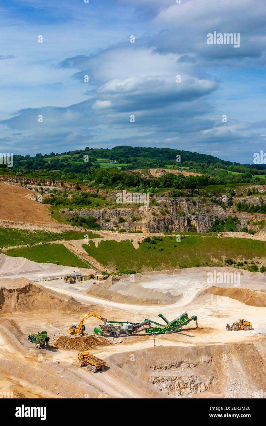 Diggers and earth moving trucks with quarrying machinery at Dene Quarry in Cromford near Matlock in the Derbyshire Dales England UK Stock Photo