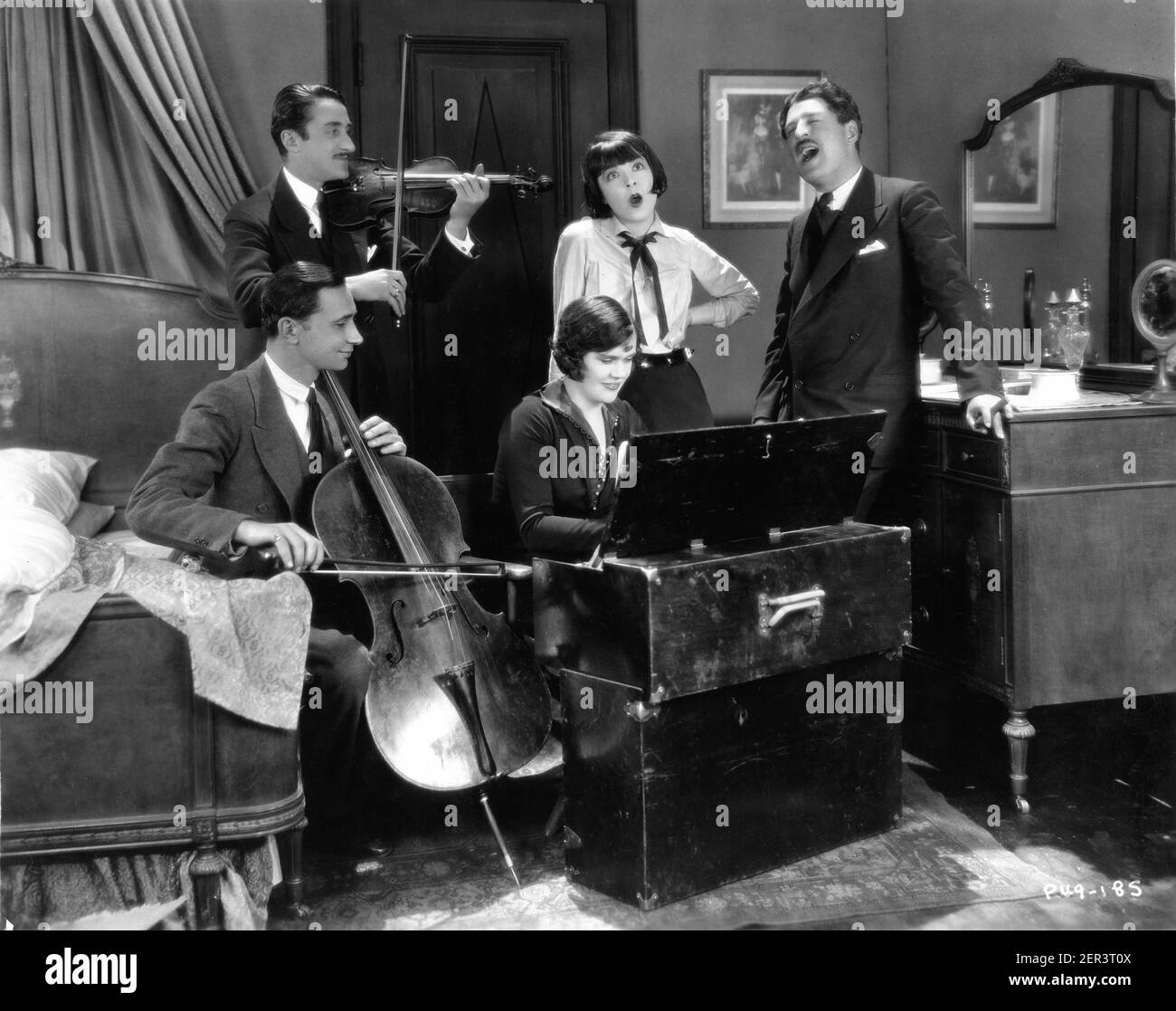 COLLEEN MOORE and Director ALFRED E. GREEN celebrate the completion of shooting by singing a song with the Mood Music Set Musicians including LEON BERLASKY (aka actor LEON BELASCO) playing violin on set candid  during filming of IRENE 1926 director ALFRED E. GREEN based on play by James Montgomery and Rex Taylor comedy construction / gag man Mervyn LeRoy First National Pictures Stock Photo