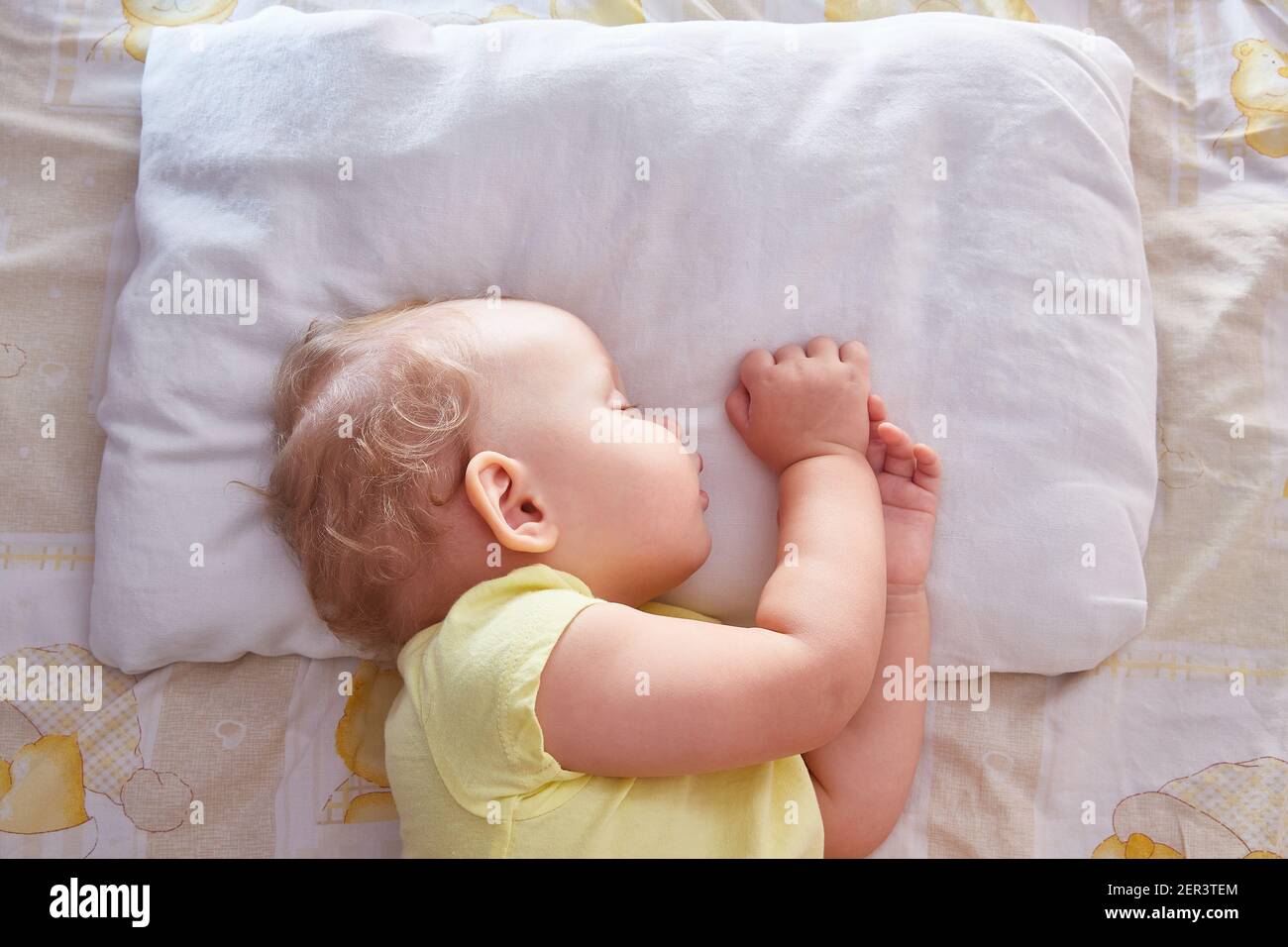 The baby sleeps on its side on a white pillow. Top view Stock Photo Alamy