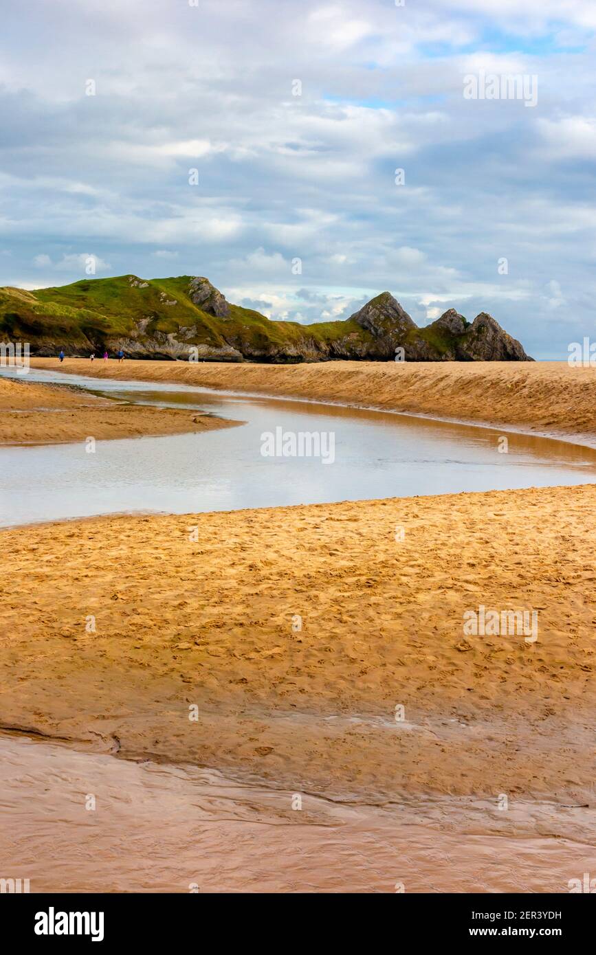 Pennard Pill a stream that flows over the sandy beach at Three Cliffs Bay on the south coast of the Gower Peninsula near Swansea in South Wales UK Stock Photo