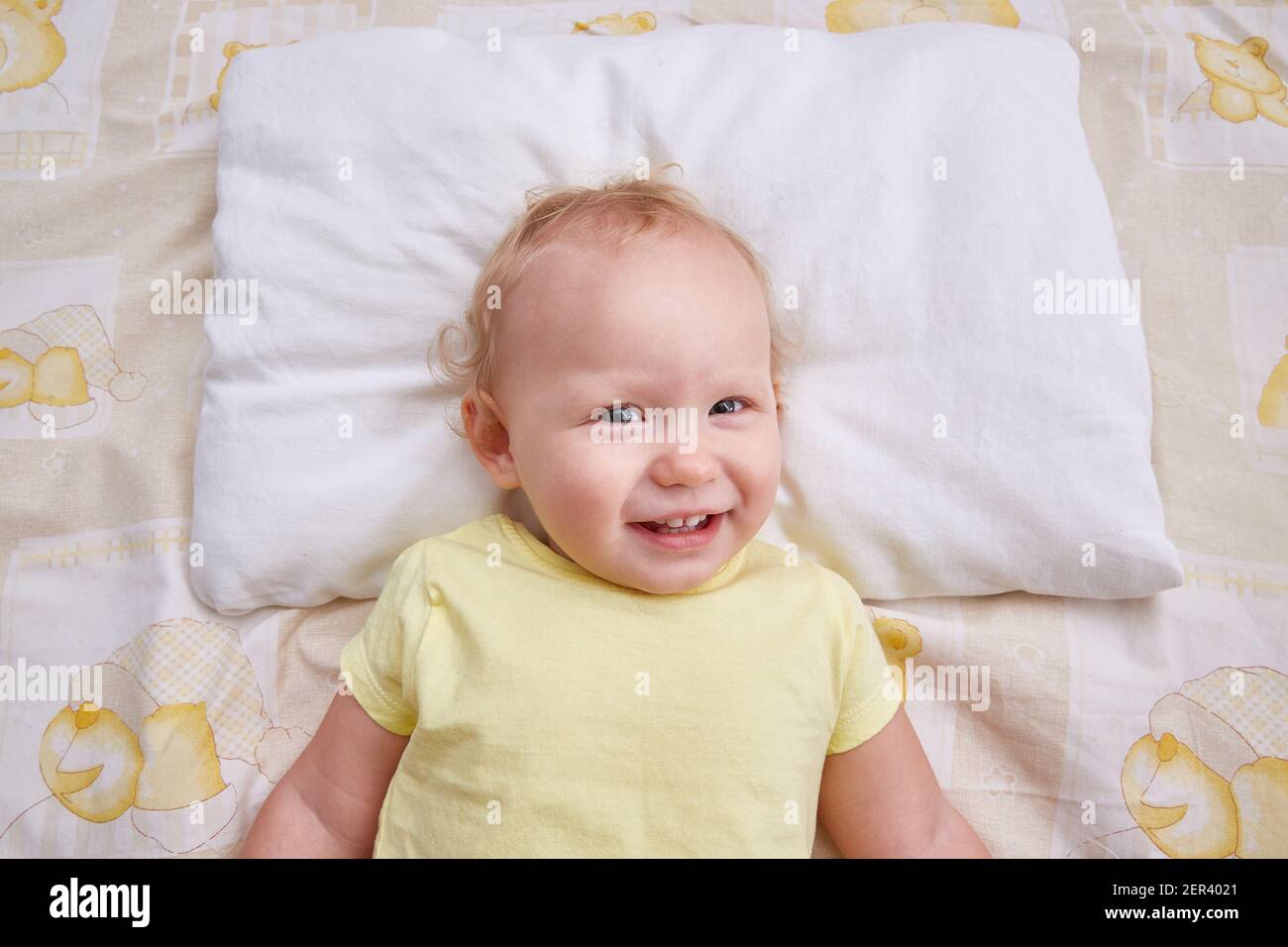 A smiling baby lies on a white pillow. pillowcase mockup. Stock Photo