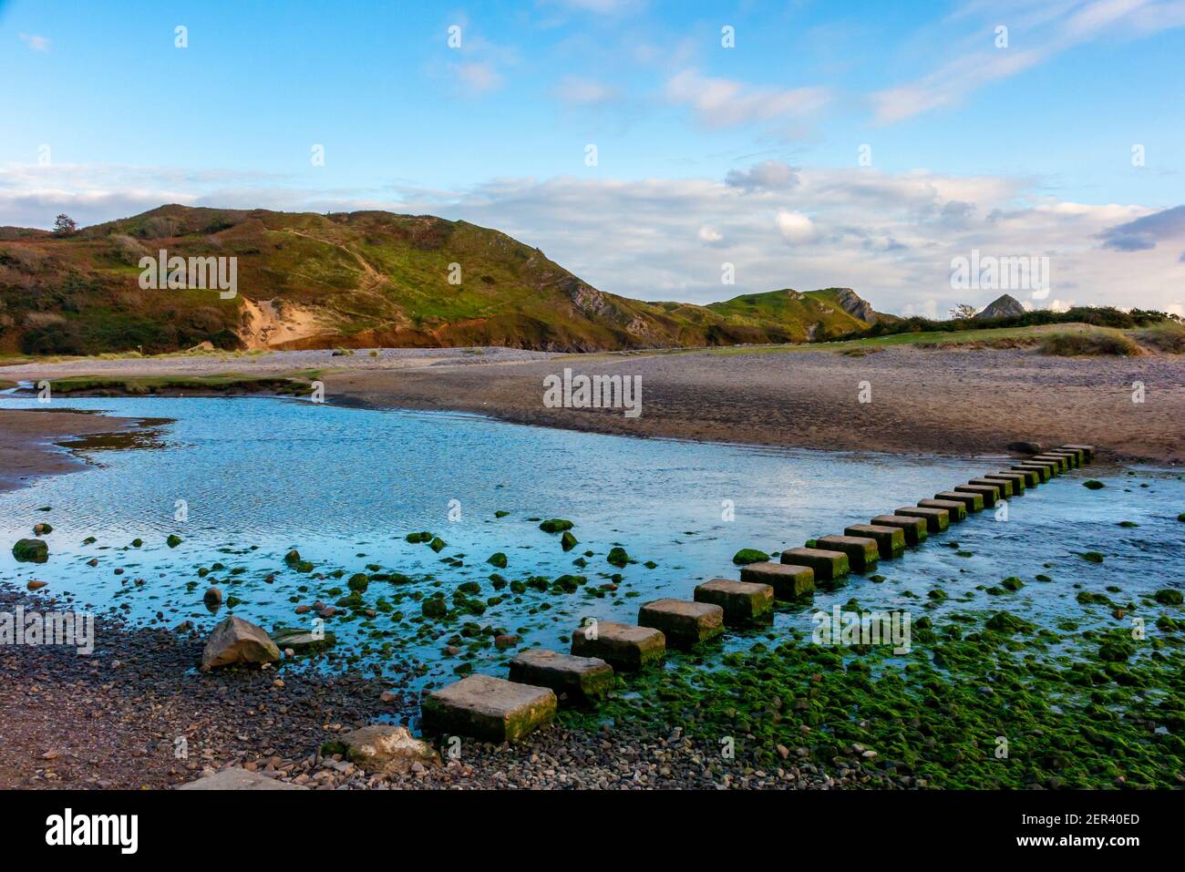 Sandy beach and stepping stones over Pennard Pill at Three Cliffs Bay on the south coast of the Gower Peninsula near Swansea in South Wales UK Stock Photo