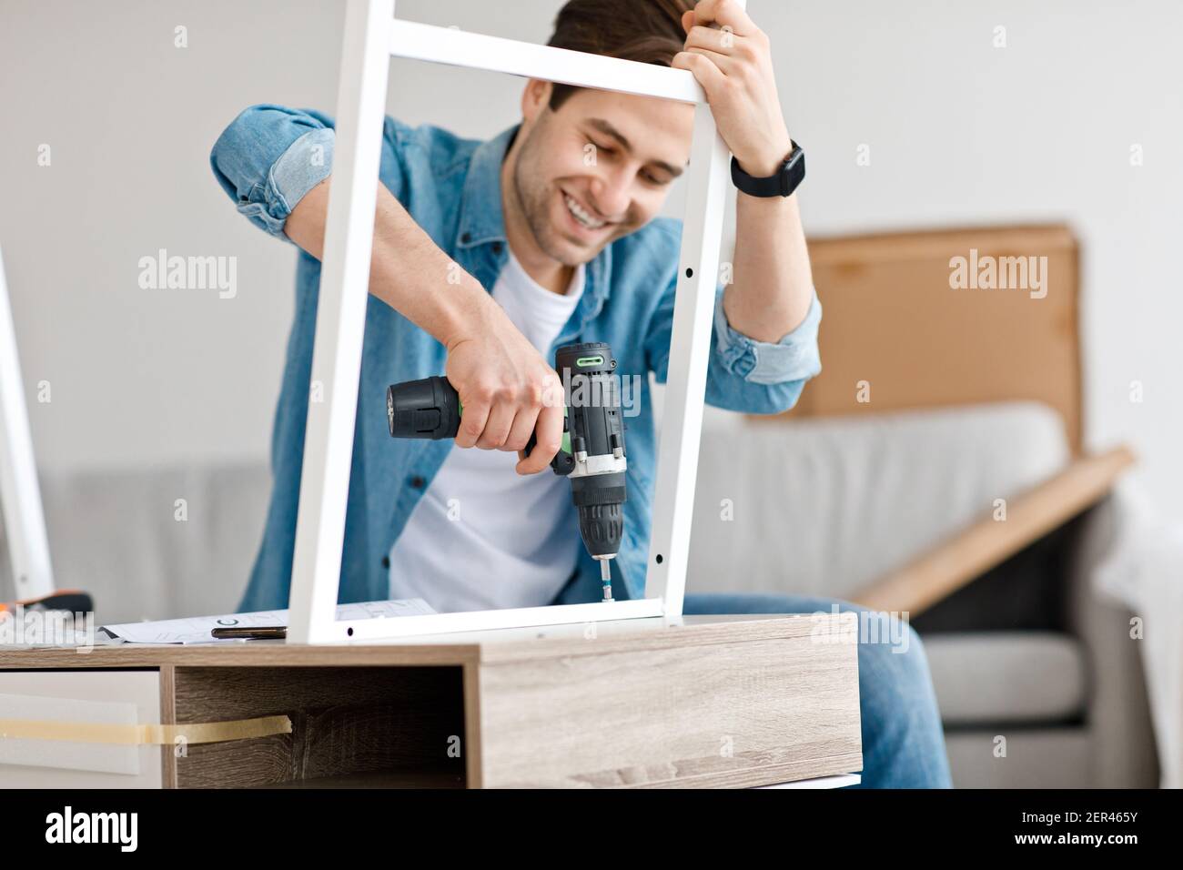 Assembling chipboard furniture using cordless screwdriver at home Stock Photo