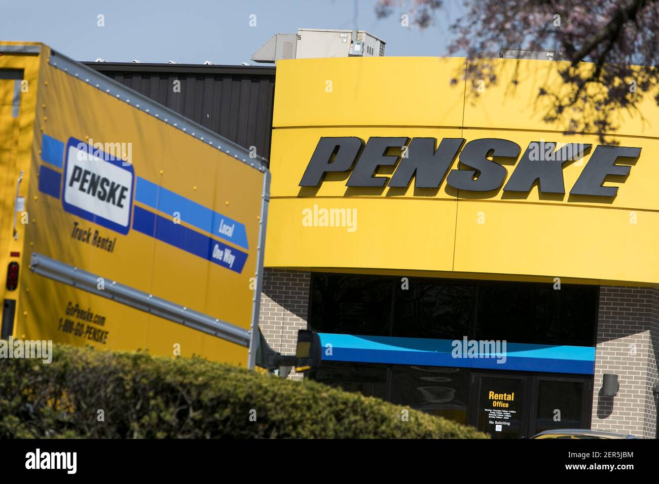 A logo sign and rental trucks outside of a facility occupied by Penske