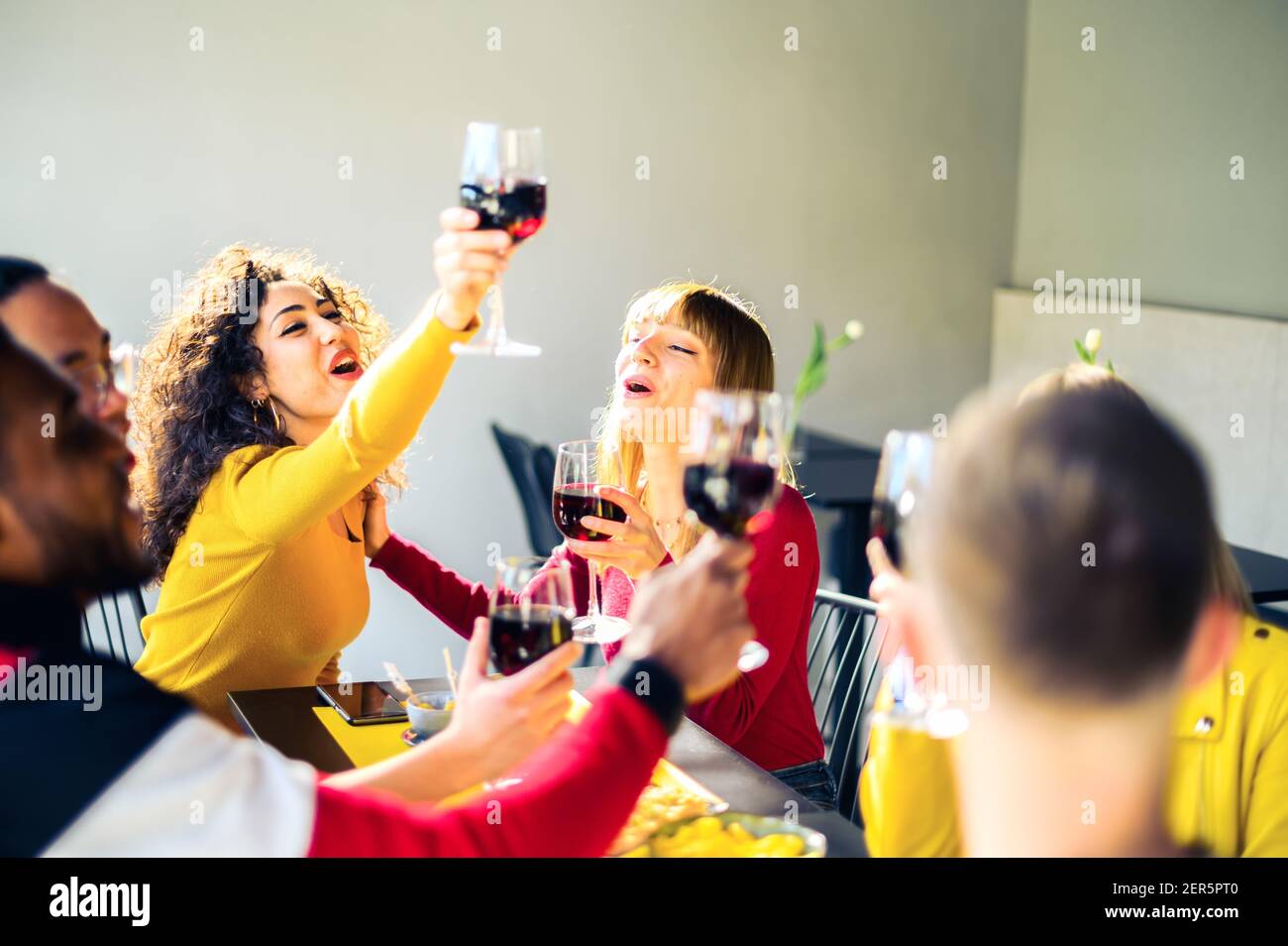 Group of multiracial friends cheering with red wine in trendy winery bar - Happy people drinking and having fun at pub restaurant  - Party and lifesty Stock Photo