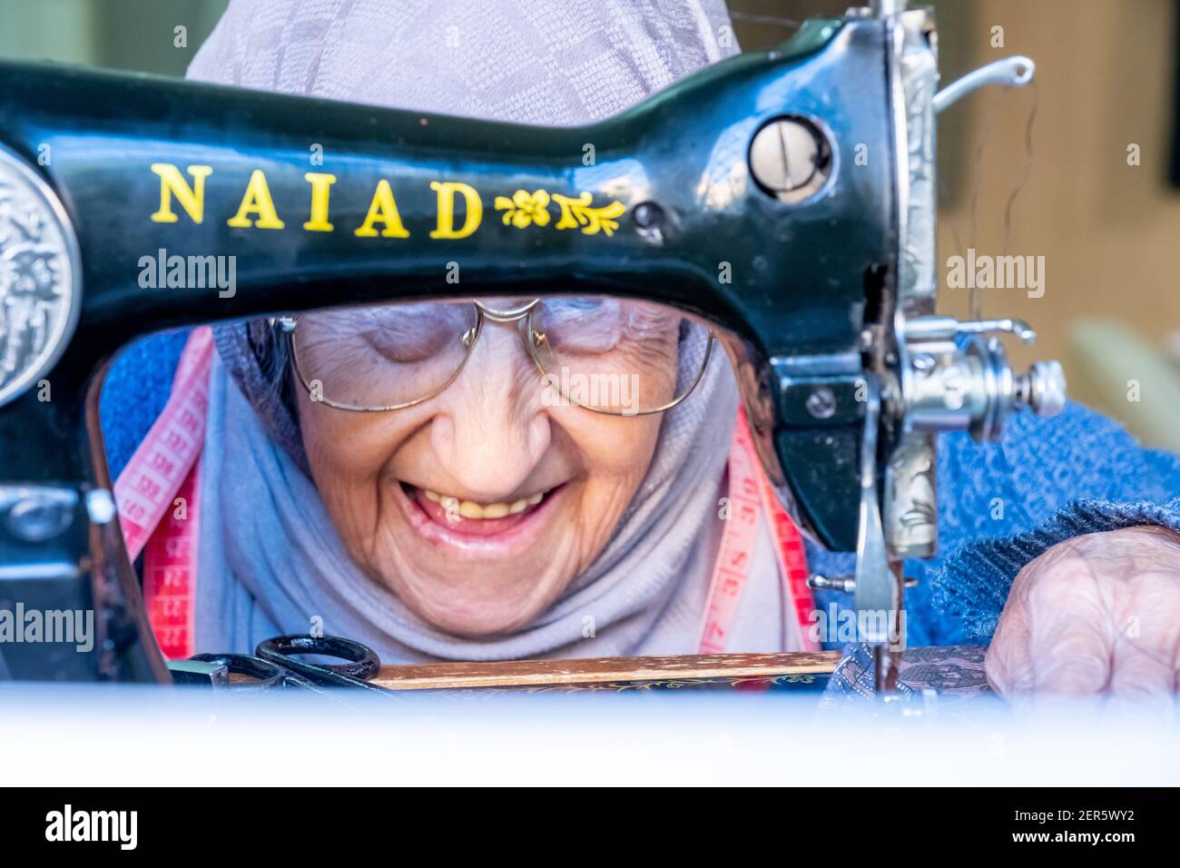 Arabic muslim old woman using old sewing machine Stock Photo