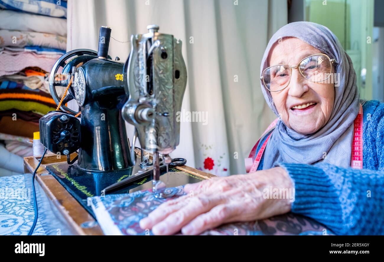 Arabic muslim old woman using old sewing machine Stock Photo