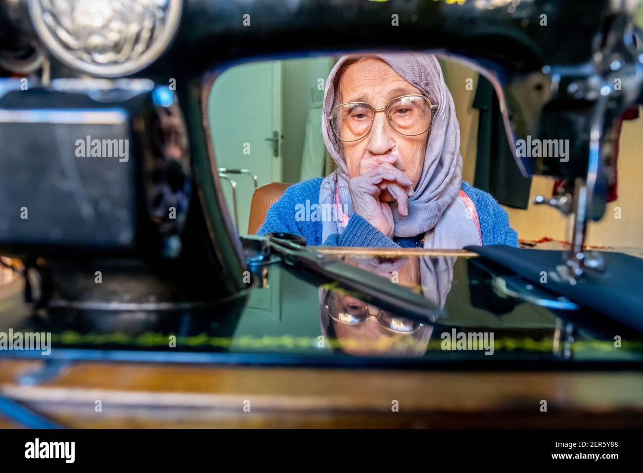 Arabic muslim old woman using old sewing machine Stock Photo