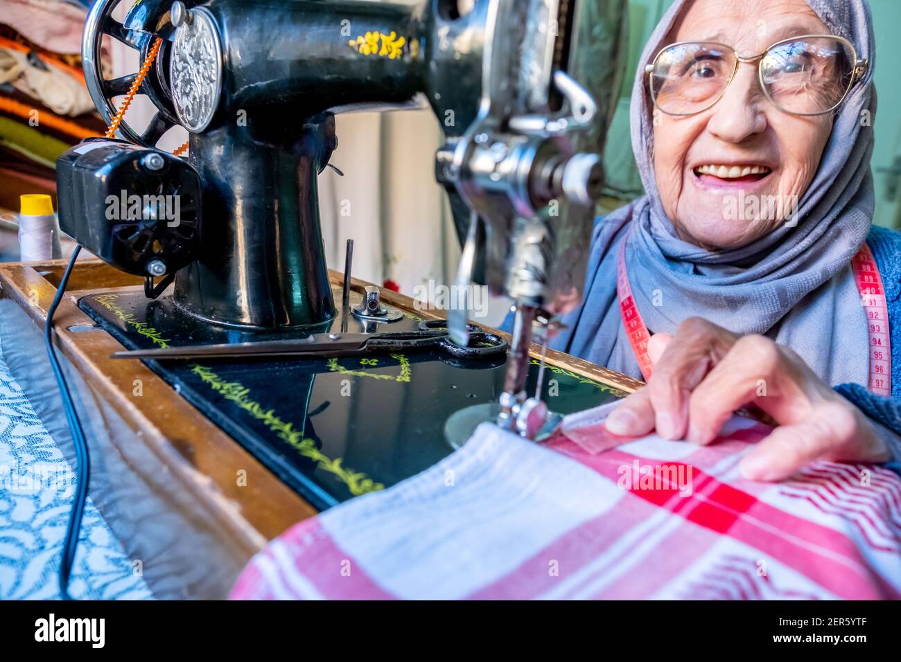 Arabic muslim old woman using old sewing machine Stock Photo