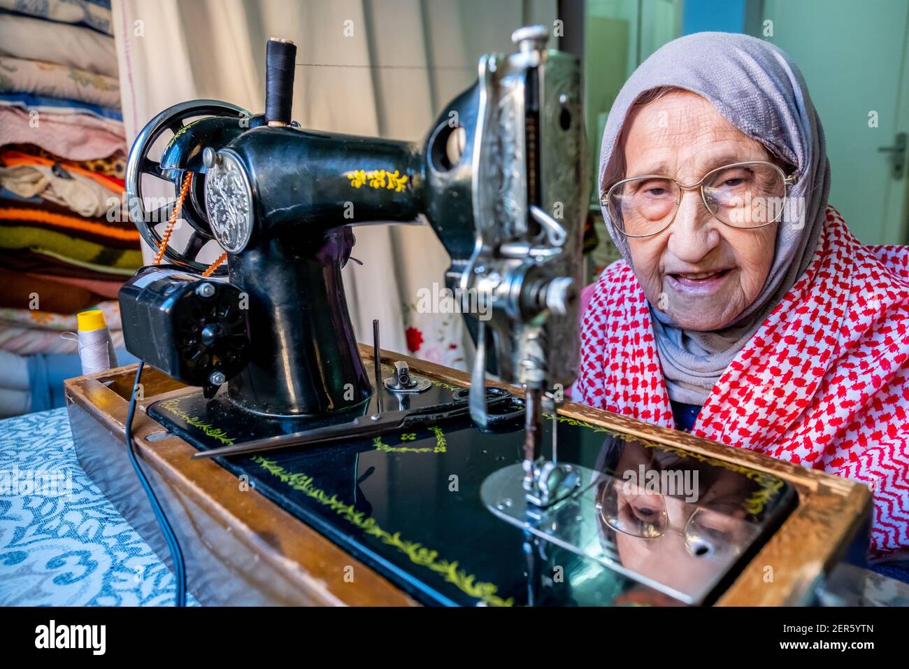 Arabic muslim old woman using old sewing machine Stock Photo