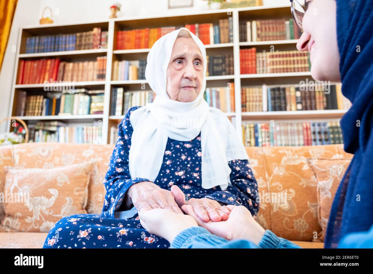 Happy arabic muslim granddaughter holding her grandmother hands Stock