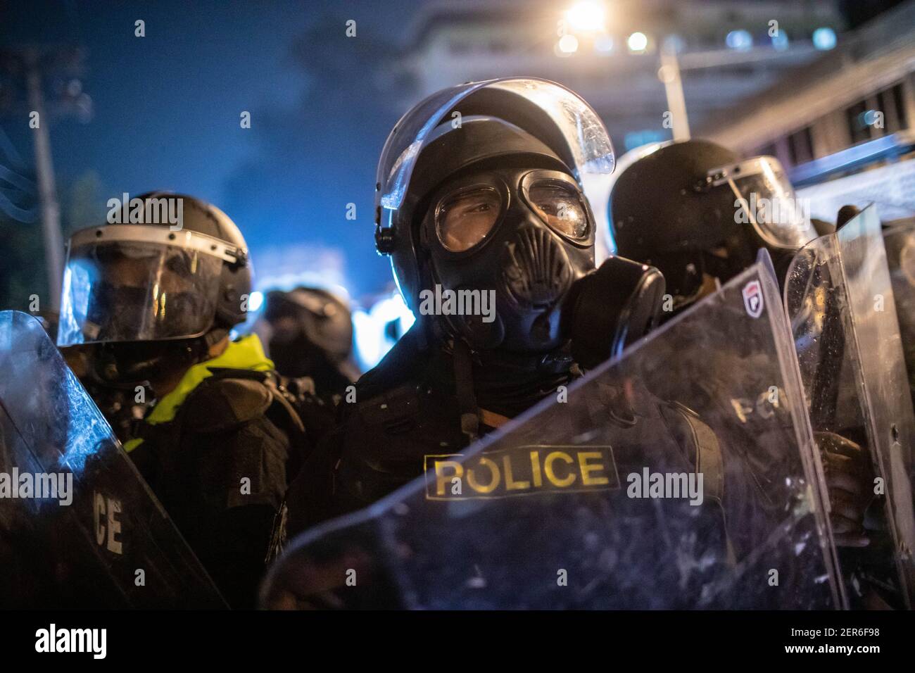 Riot police wearing gas mask stand guard during an anti-government demonstration in Bangkok.Thousands of pro-democracy protesters gathered at Vibhavadi Rangsit Road in front of the 1st Infantry Regiment near the Prime Minister house demanding the resignation of Thailand Prime Minister and the reform of the monarchy in Bangkok, Thailand. The protesters also denounced the use of the ‘Lese Majeste law’ under the section 112 of the penal code. The protest organized by ‘FreeYouth’ ended up with several clashes, the use of water cannon, tear gas, rubber bullet, which had left a total of 18 injured. Stock Photo