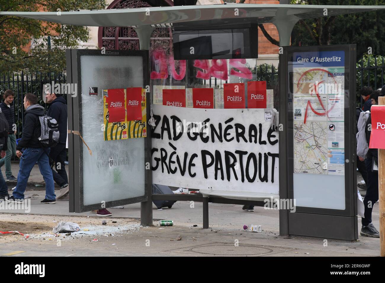 Riot police stand in front of a damaged bus stop after clashs broke out ...