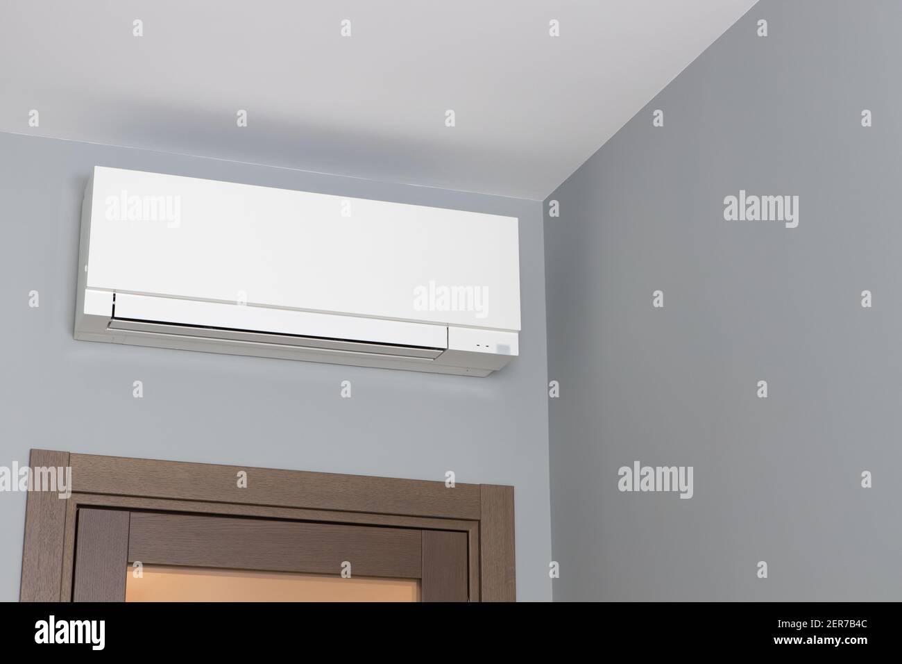 White air conditioning on gray wall inside room in apartment over door