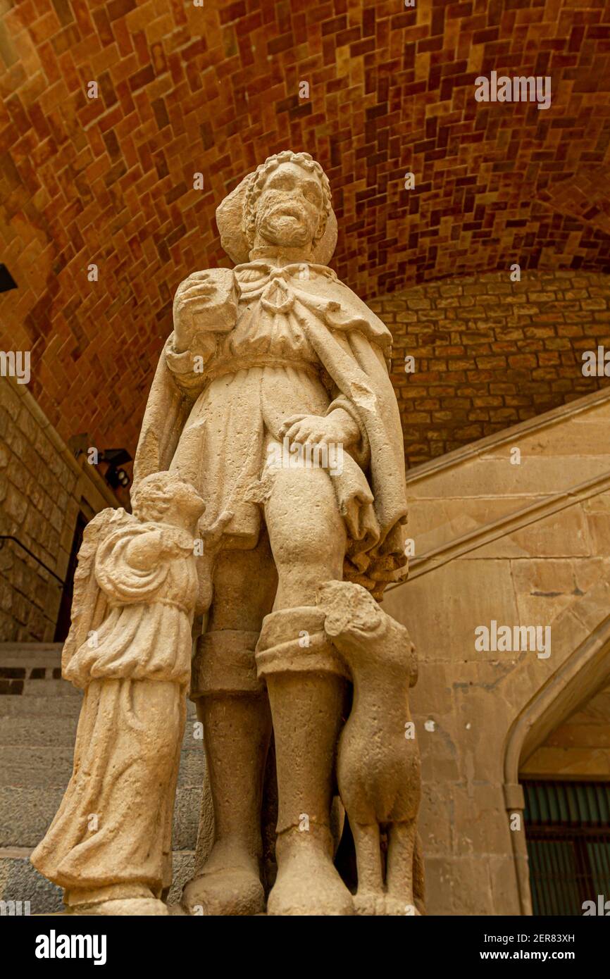 Close up image of the statue outside of the main entrance of the medieval Old Hospital de la Santa Creu, Biblioteca de Catalunya with arched walls of Stock Photo