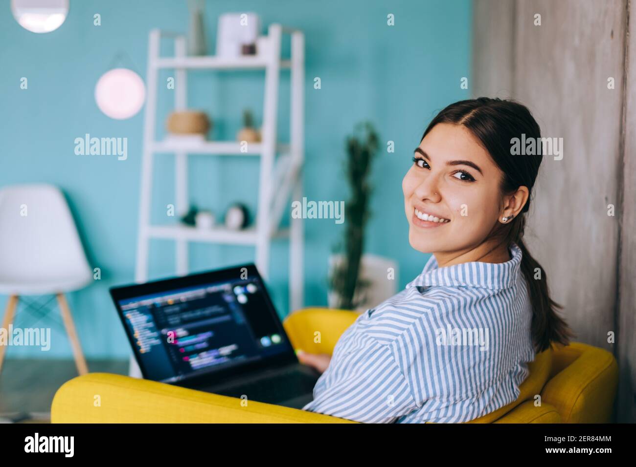 Portrait of young woman mobile developer with laptop, writes program code on a computer, programmer work. Stock Photo