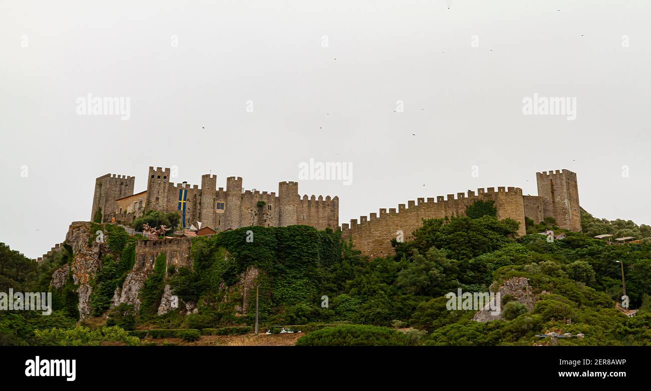 Obidos, Portugal is a walled city with well preserved castle and walls surrounding the hilltop settlement. These medieval stone structures as well as Stock Photo