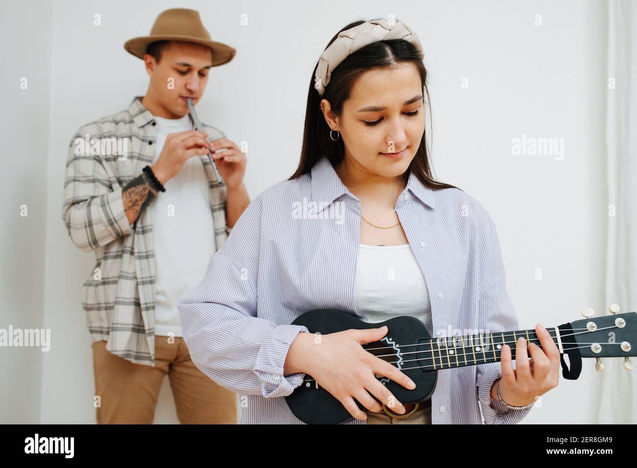 Cute girl playing ukulele in the background of a man playing the Irish flute Stock Photo