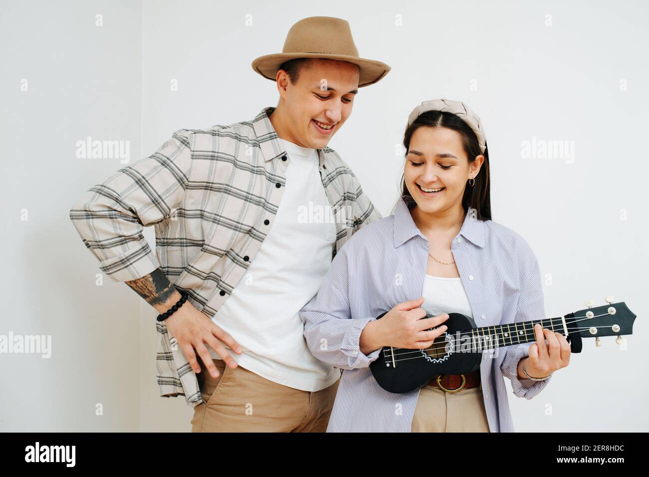 Funny guys sing and play the ukulele together on a gray background Stock Photo