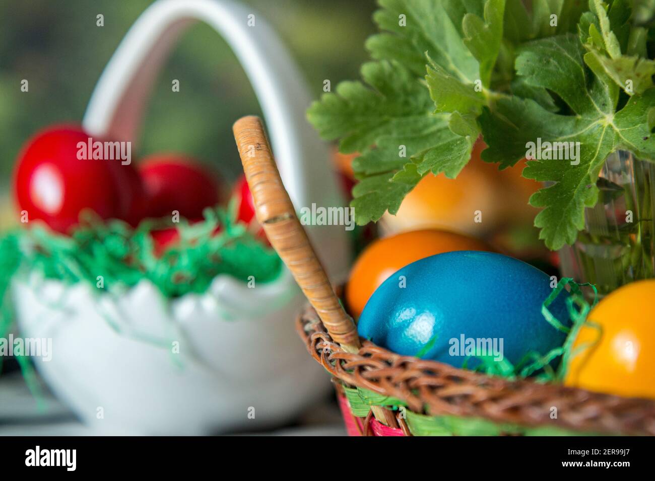 Easter table setting with colored red eggs, bread, green branches decorated, over white plank wooden table with textile tablecloth Stock Photo