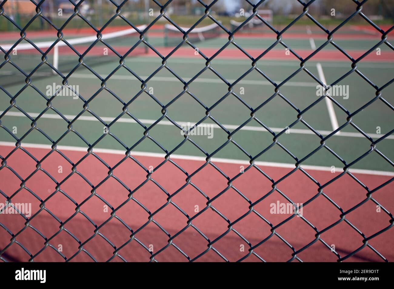 Looking through chain link fence towards private tennis courts. England Stock Photo