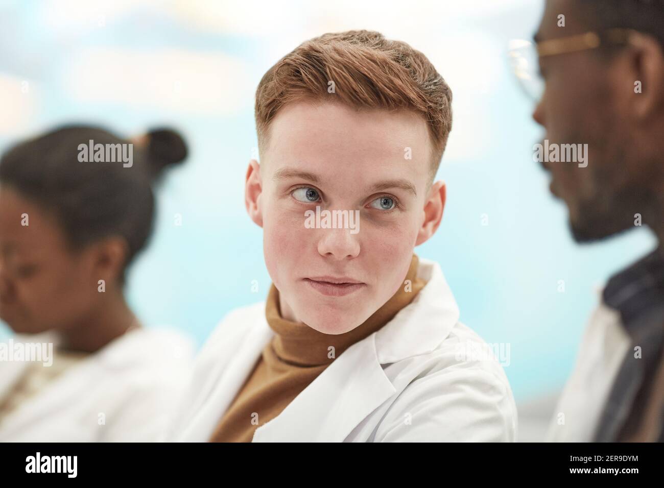 Close up portrait of young man wearing lab coat while sitting in row in audience and listening to lecture on medicine in college, copy space Stock Photo