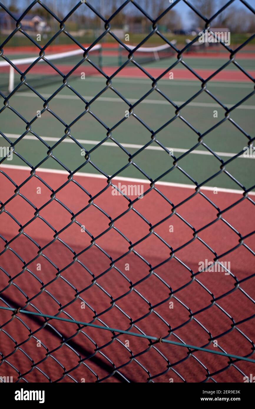 Looking through chain link fence towards empty tennis courts. England Stock Photo